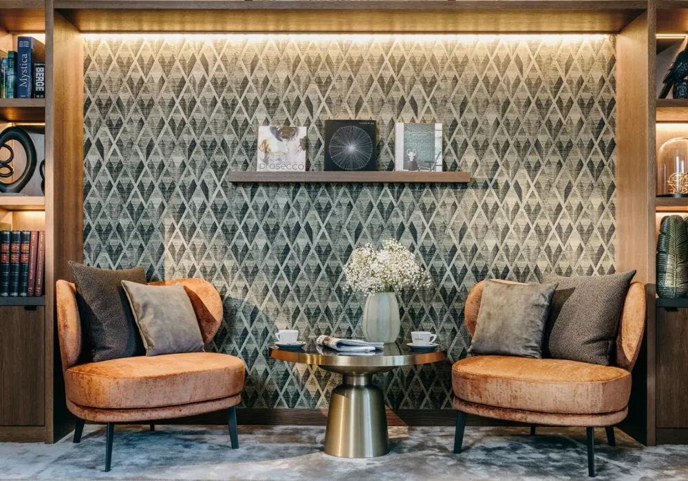 Elegant reading corner at Grand Tirolia Kitzbühel featuring cozy armchairs, stylish wall design, and decorative shelves