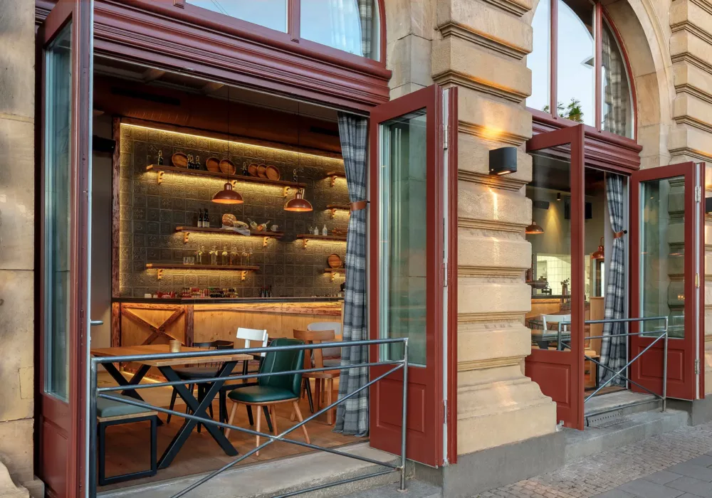 Stylish tavern with an open facade, rustic wooden furniture, a warmly lit bar, and modern industrial design elements.