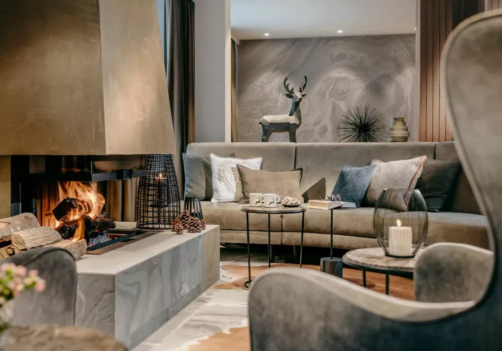 Cozy fireplace lounge at Grand Tirolia Kitzbühel featuring stylish furnishings, a warm fire, and elegant decor