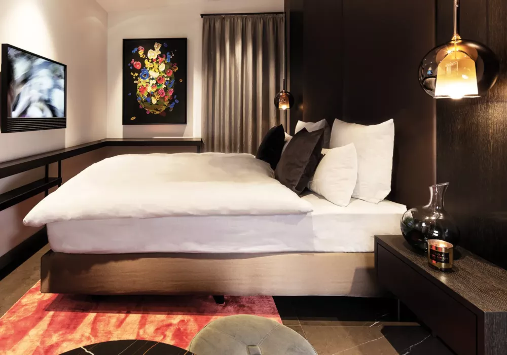 Luxurious bedroom in Private Penthouse Berlin featuring designer lighting, dark accents, and modern artwork on the wall