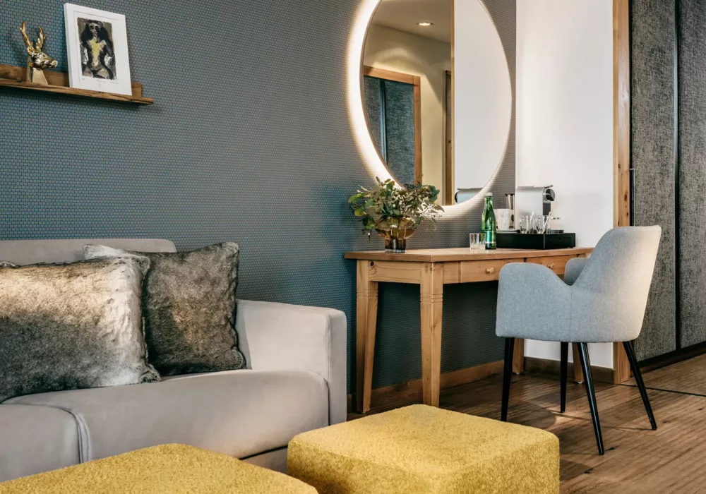 Stylish room corner at Grand Tirolia Kitzbühel featuring a backlit mirror, wooden desk, and cozy seating area